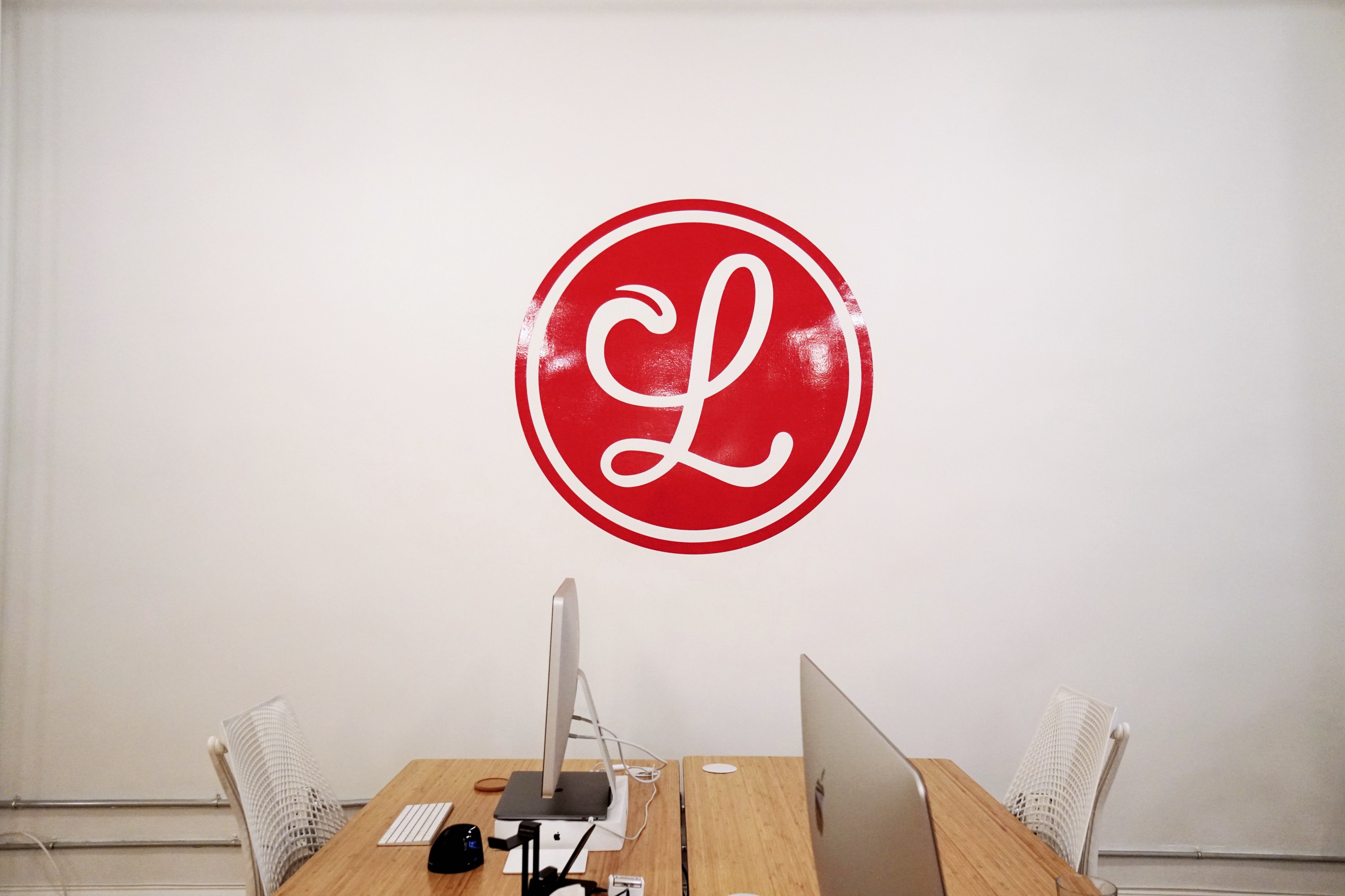 A photo of desks at Lickability, and a wall decal of the Lickability logo.