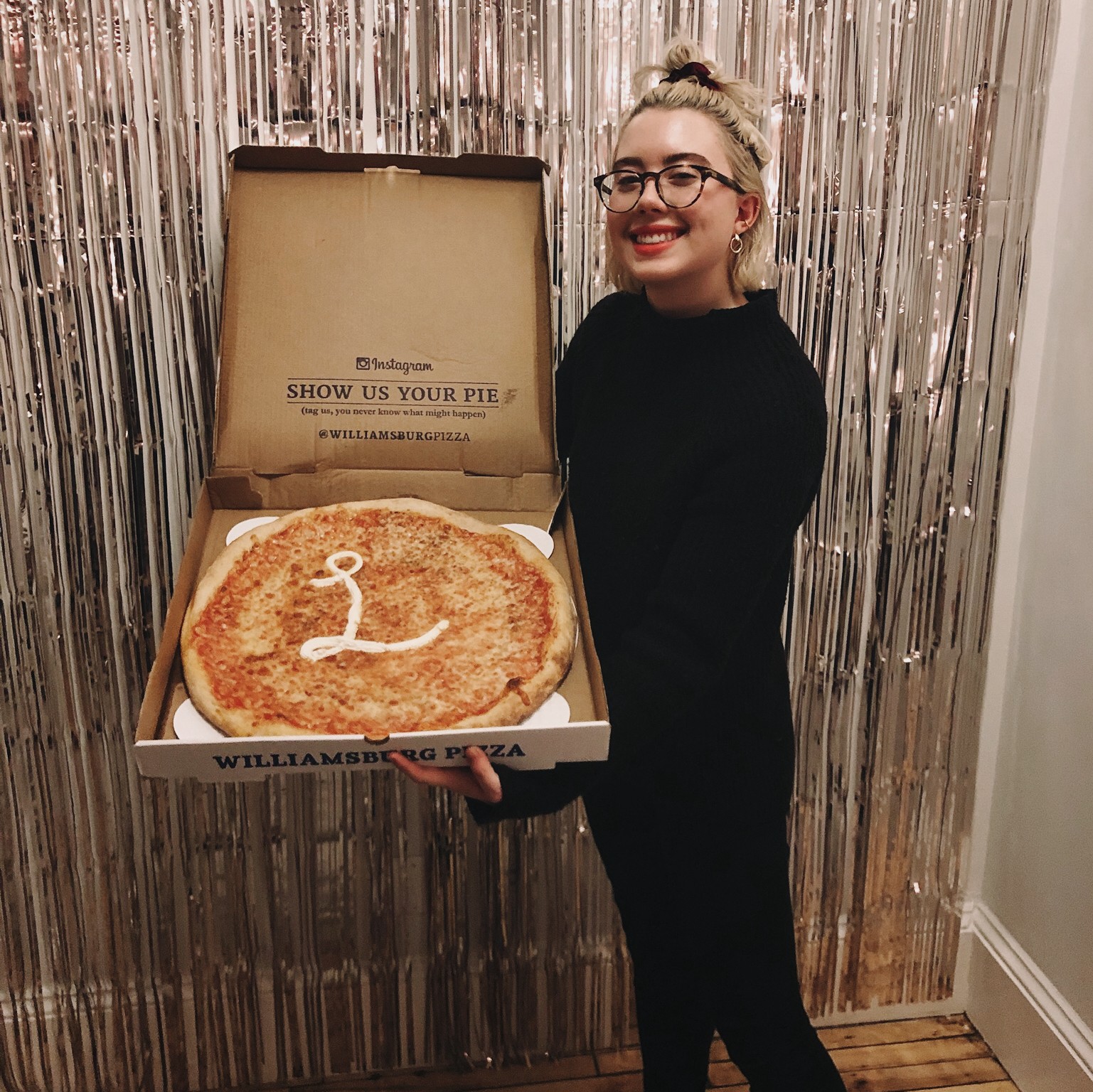 Jillian holding a pizza with the Lickability logo on it.